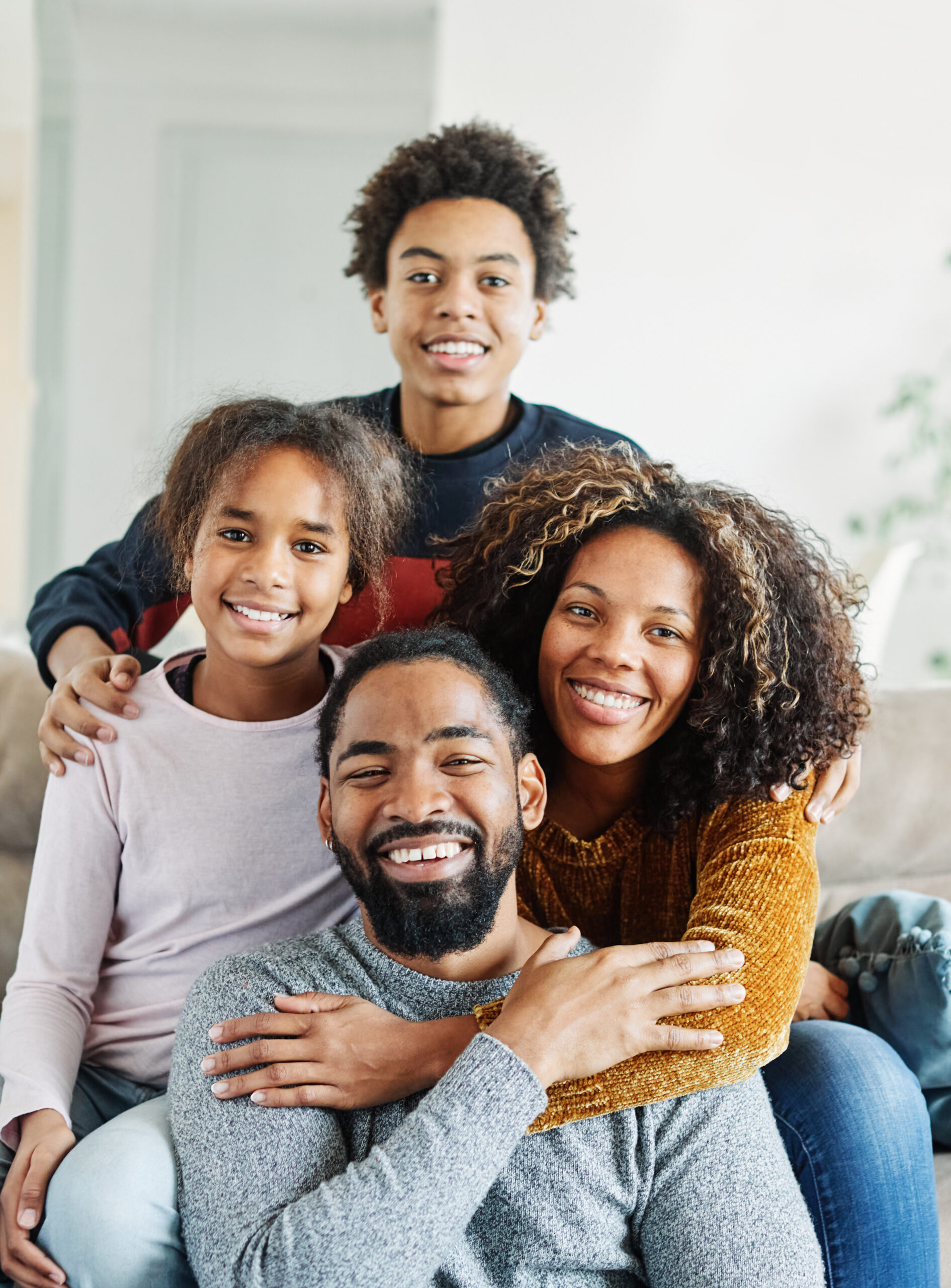 Portrait of a happy black family mother father and kids at home on couch