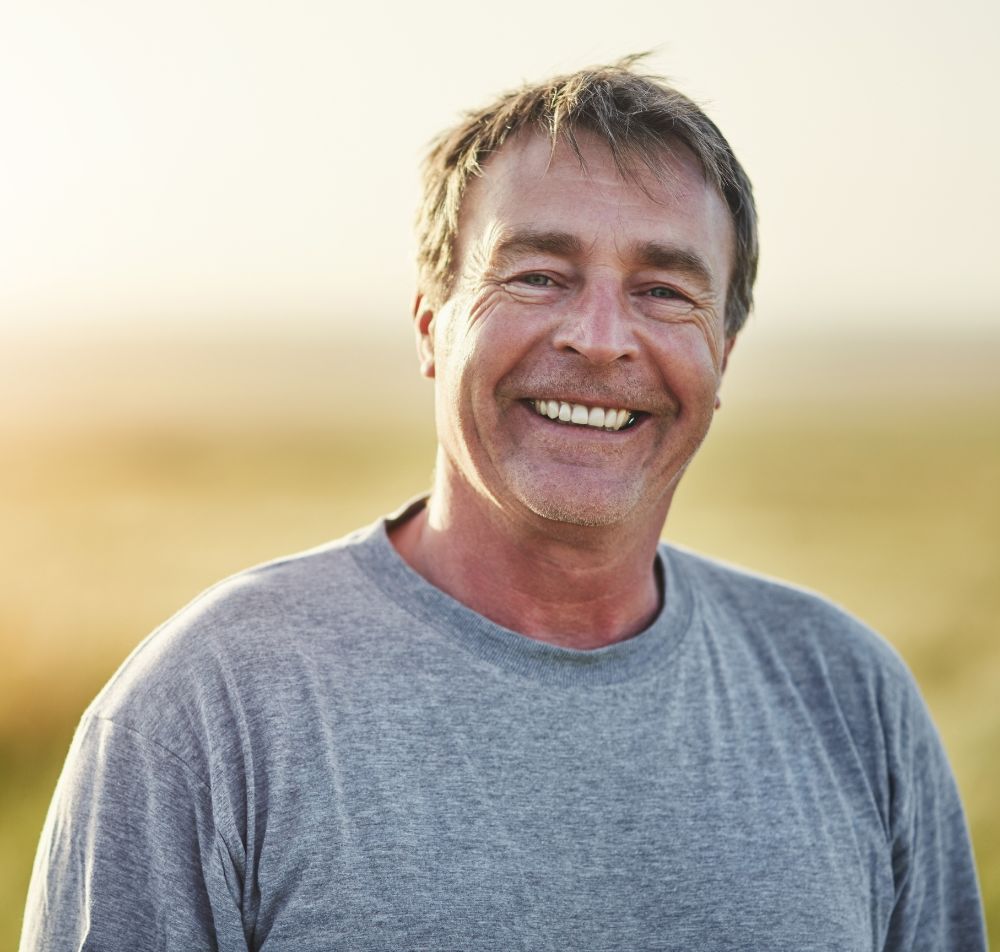 Man standing in open field smiling