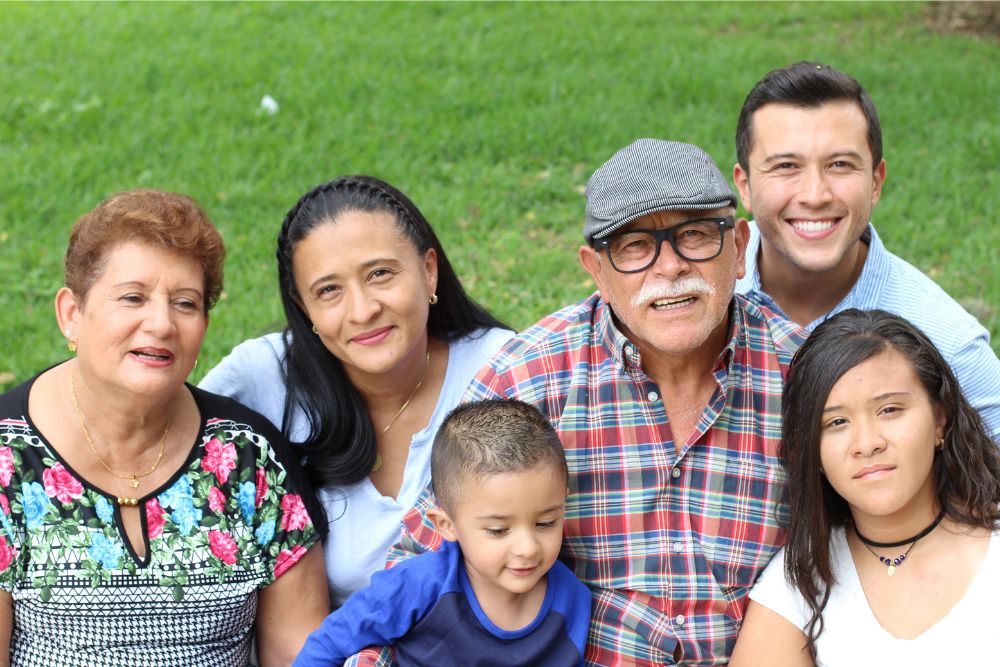 Multi generational family sitting on the grass on a clear sunny day.