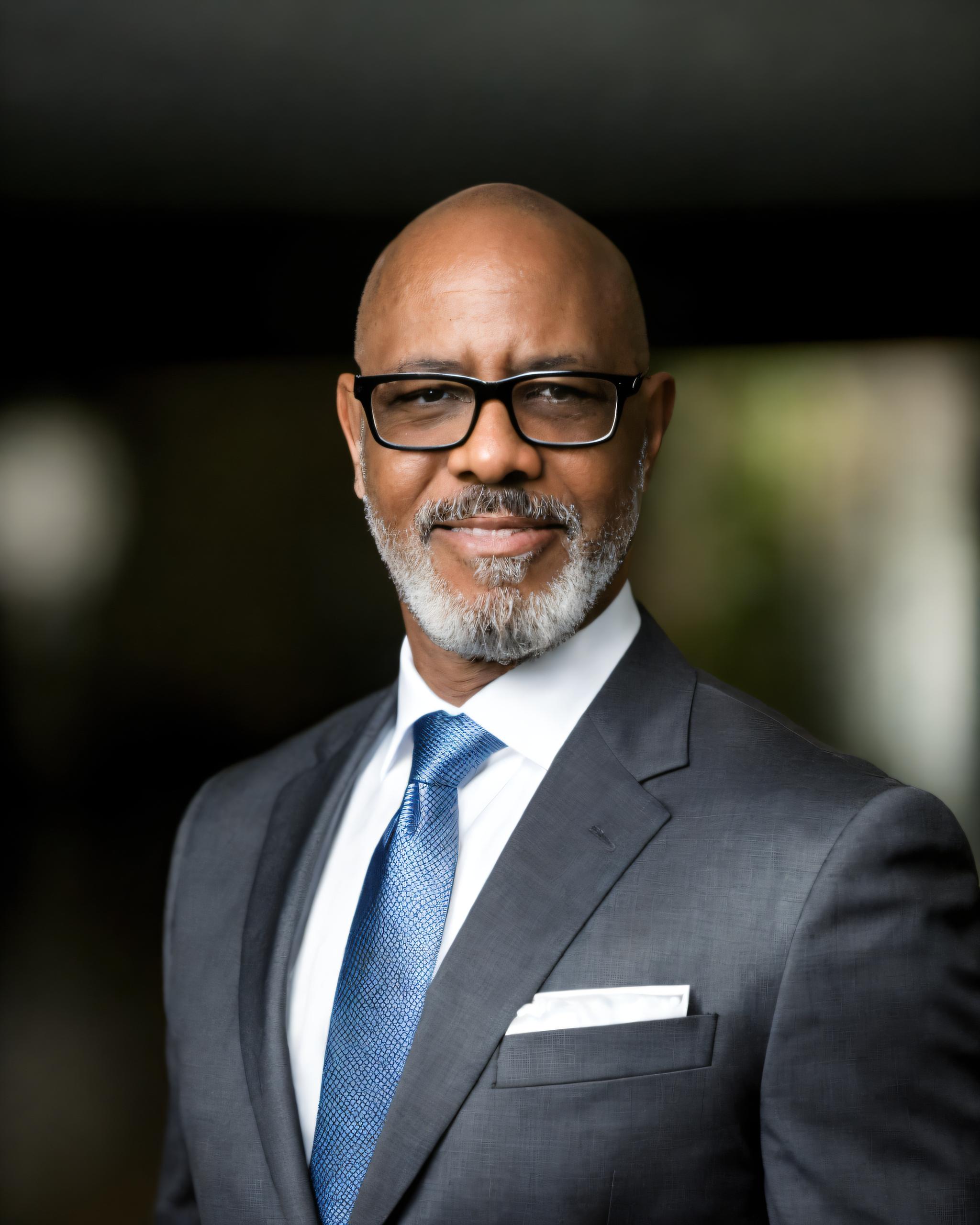 Attractive man wearing a grey suit with a blue tie.